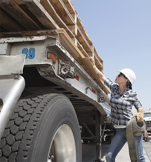 Female worker strapping down pallets on flatbed truck